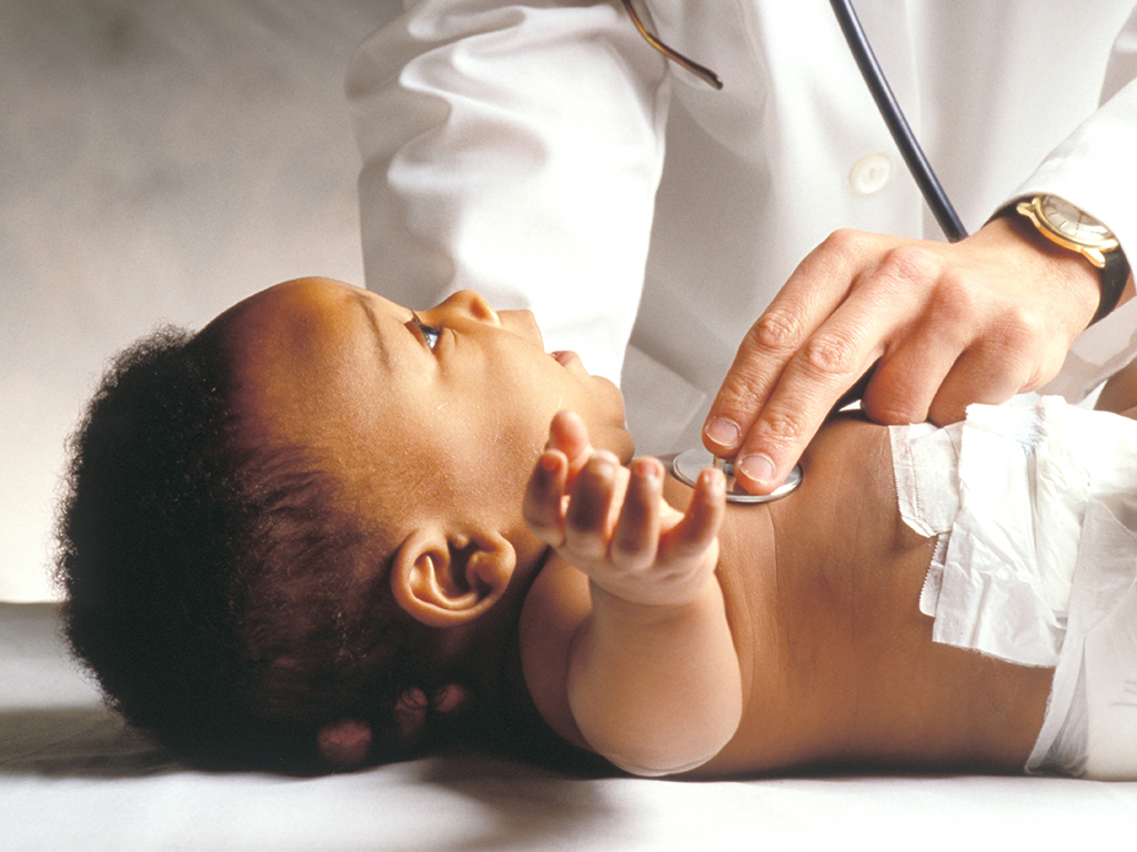 Doctor using stethoscope to examine infant